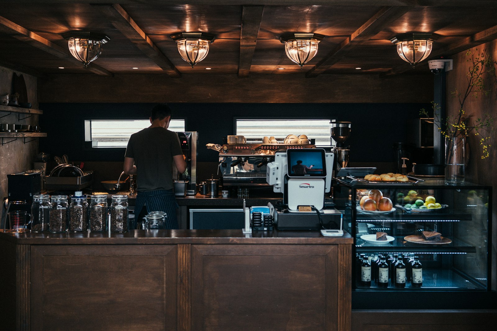 A barista working behind a warmly lit espresso machine